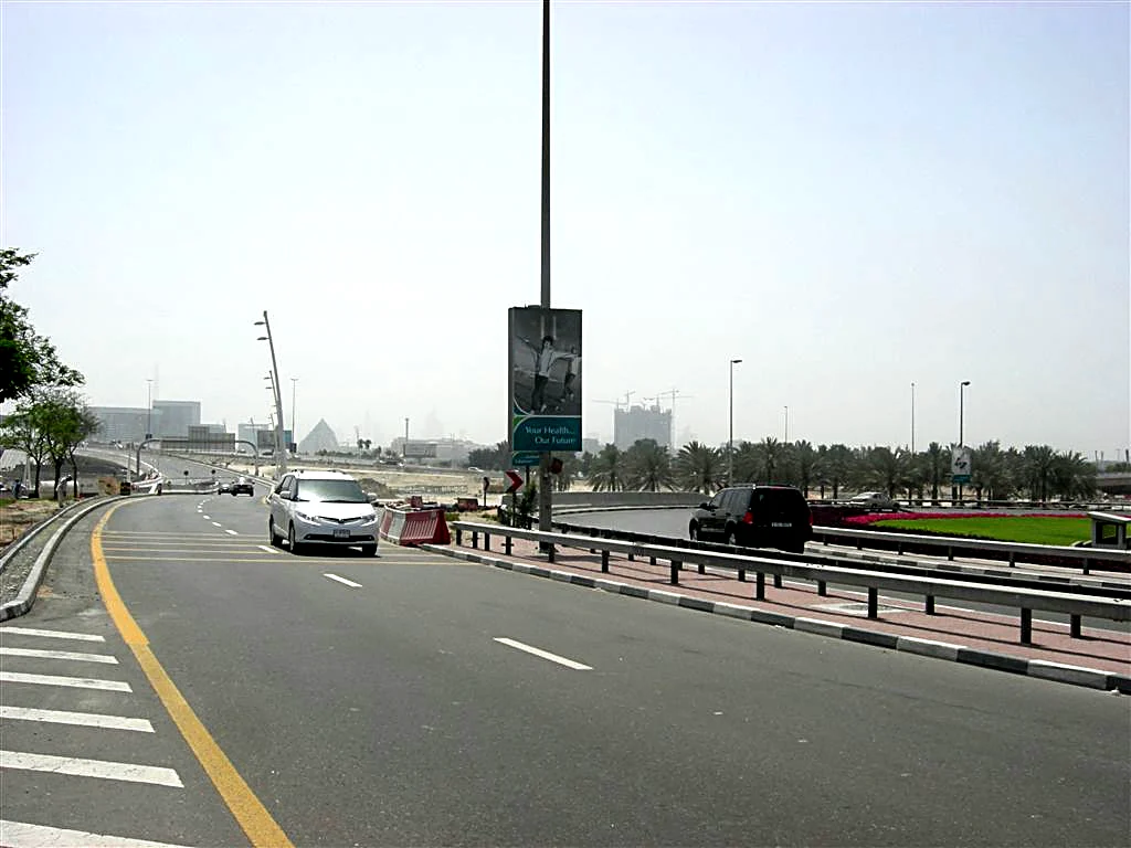 A lamp-post banner beside a road, far off.